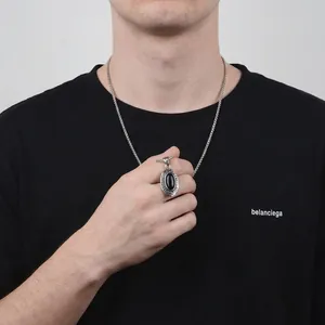 Hip hop style silver necklace featuring an oval black gemstone pendant on a male model