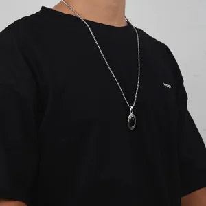 Detail of hip hop style necklace with black oval gemstone pendant on silver chain