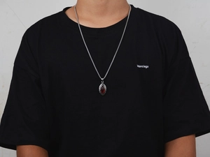 Close-up of hip-hop oval pendant necklace with red gemstone and vintage engraving