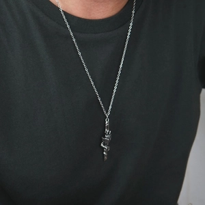 Gros plan d'un collier pendentif dragon aux écailles détaillées sur un t-shirt noir