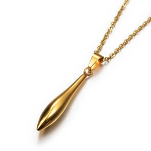Detail of polished gold torpedo pendant with elegant link chain on white reflective surface