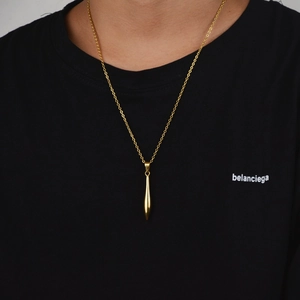 Minimalist gold bullet pendant necklace in stainless steel shown on a male model