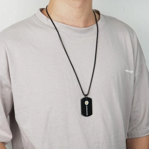 Close-up of black titanium dog tag necklace with white daisy and Marguerite text on male model