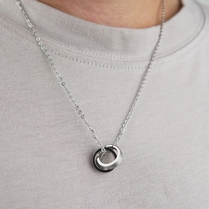 Gros plan du collier avec anneaux imbriqués argent et noir portés sur un t-shirt