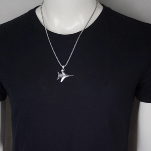 Collier pendentif avion de chasse en acier titane poli sur un t-shirt noir