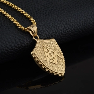 Gros plan du pendentif maçonnique en forme de bouclier doré sur fond de cuir noir