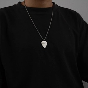 Minimalist silver guitar pick pendant necklace with star engraving worn by a model