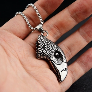 Close-up of vintage silver eagle head pendant with detailed feathers and steel chain