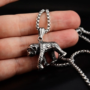 Gros plan d'un pendentif singe en argent vieilli sur une chaîne box en acier inoxydable