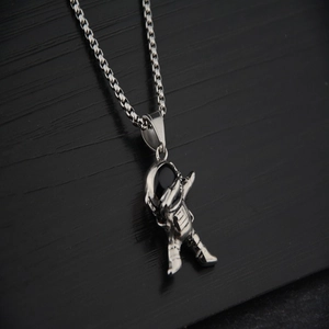 Close-up of a silver astronaut pendant in dabbing pose with a sleek square link chain