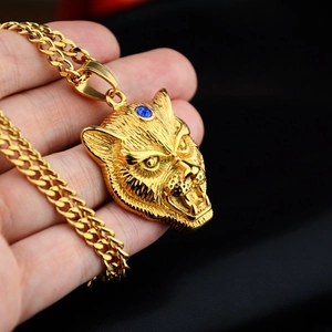 Detail of gold leopard head pendant with blue gems on a classic Cuban link chain