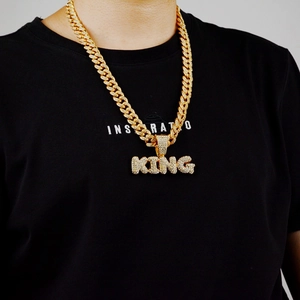 Detail of hip hop gold Cuban link chain with iced-out KING letter pendant for men