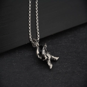 Trendy astronaut pendant necklace with silver box chain on dark grey rock texture