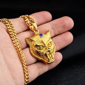 Detailed macro view of a gold leopard head pendant with blue gemstone on a Cuban link chain