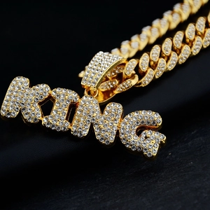 Macro detail of iced-out gold KING letter pendant with sparkling crystal paved Cuban chain