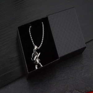 Astronaut pendant necklace in silver metal on a black textured jewelry box