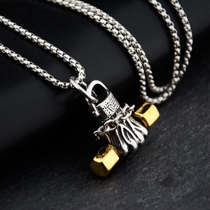 Macro detail of bicolored gold and silver dumbbell pendant with square box chain