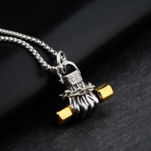 Detailed close-up of a silver fist pendant holding a golden dumbbell on a box chain