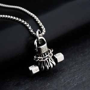 Macro view of vintage silver dumbbell fist pendant with oxidized steel detailing