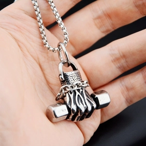 Close-up of vintage steel fist dumbbell pendant necklace held in hand for scale
