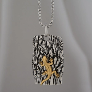 Macro shot of silver tree bark texture pendant with gold lizard embossed detail