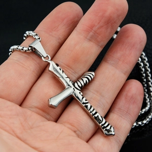 Detailed close-up of a vintage cross pendant with engraved texture on a silver box chain