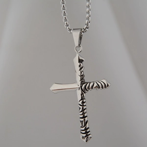 Detailed macro view of silver cross pendant with gothic thorn texture and box chain