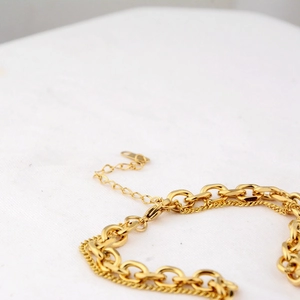Double-layered gold chain necklace with a smiling face pendant and adjustable lobster clasp