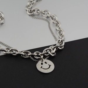 Detailed macro of silver double-layered chain necklace with a smiley face love life charm