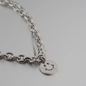 Detail shot of silver double-layered necklace with smiley face and Love Life engraving