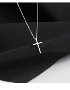 Macro shot of polished silver cross pendant necklace with mirror finish on black texture
