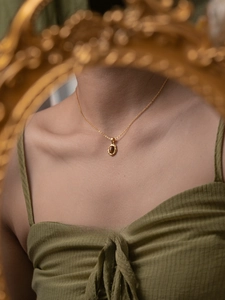 Gros plan d'un collier pendentif ambre en argent S925 avec chaîne dorée sur un mannequin