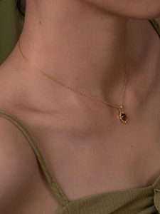Détail d'un collier en argent s925 doré avec pendentif ambre sur le cou d'un mannequin