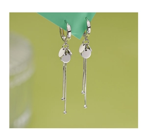 Detail of silver drop earrings featuring flat disks and long snake chain tassels with beads