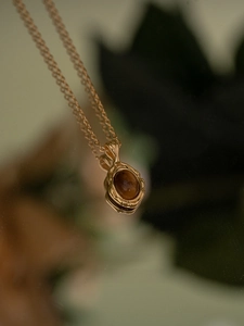 Détail d'un pendentif en ambre argent S925 avec texture dorée fondue sur fond naturel