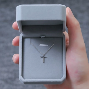 Polished silver cross pendant necklace displayed in a grey velvet jewelry gift box