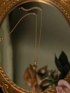 Vue détaillée du collier en argent s925 doré avec pendentif ambre devant un miroir vintage