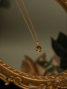 Gros plan détaillé du collier pendentif ambre sur un miroir vintage avec éclairage élégant