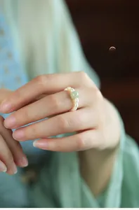 Detailed view of handmade pearl ring with a green jade bead on a finger