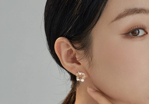 Close-up of elegant gold wreath stud earrings with white pearls and sparkling zircons