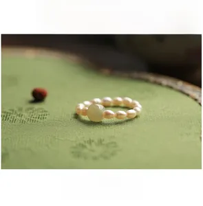 Detail of vintage pearl ring featuring large light green gemstone on embroidered fabric