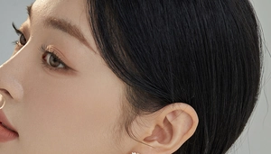 Detailed close-up of an elegant wreath-shaped pearl earring on a model's earlobe
