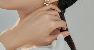 Close-up of elegant gold wreath stud earrings with pearls worn by a model