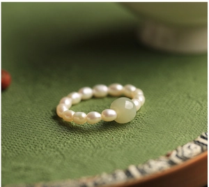 Detailed macro view of vintage pearl beaded ring with green jade bead on silk
