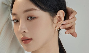 Close-up of elegant gold wreath stud earrings with white pearls and small crystals