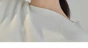 Detailed macro view of the ribbed knit fabric texture on the cream white top