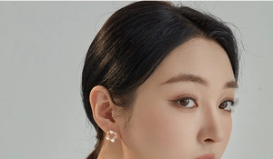 Close-up of a hollow wreath stud earring with pearls and crystals on a model ear