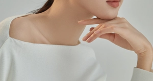 Detail of elegant off-shoulder cream knit sweater showing ribbed texture and neckline