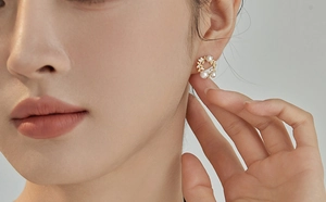 Macro shot of gold hollow wreath earrings with elegant pearls and small zirconias