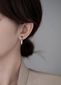 Close-up of 925 sterling silver feather drop earrings with black zircon on model